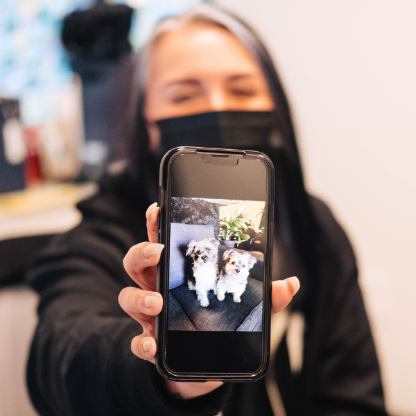 A veterinary technician holds up a smart phone showing a photo of her pets
